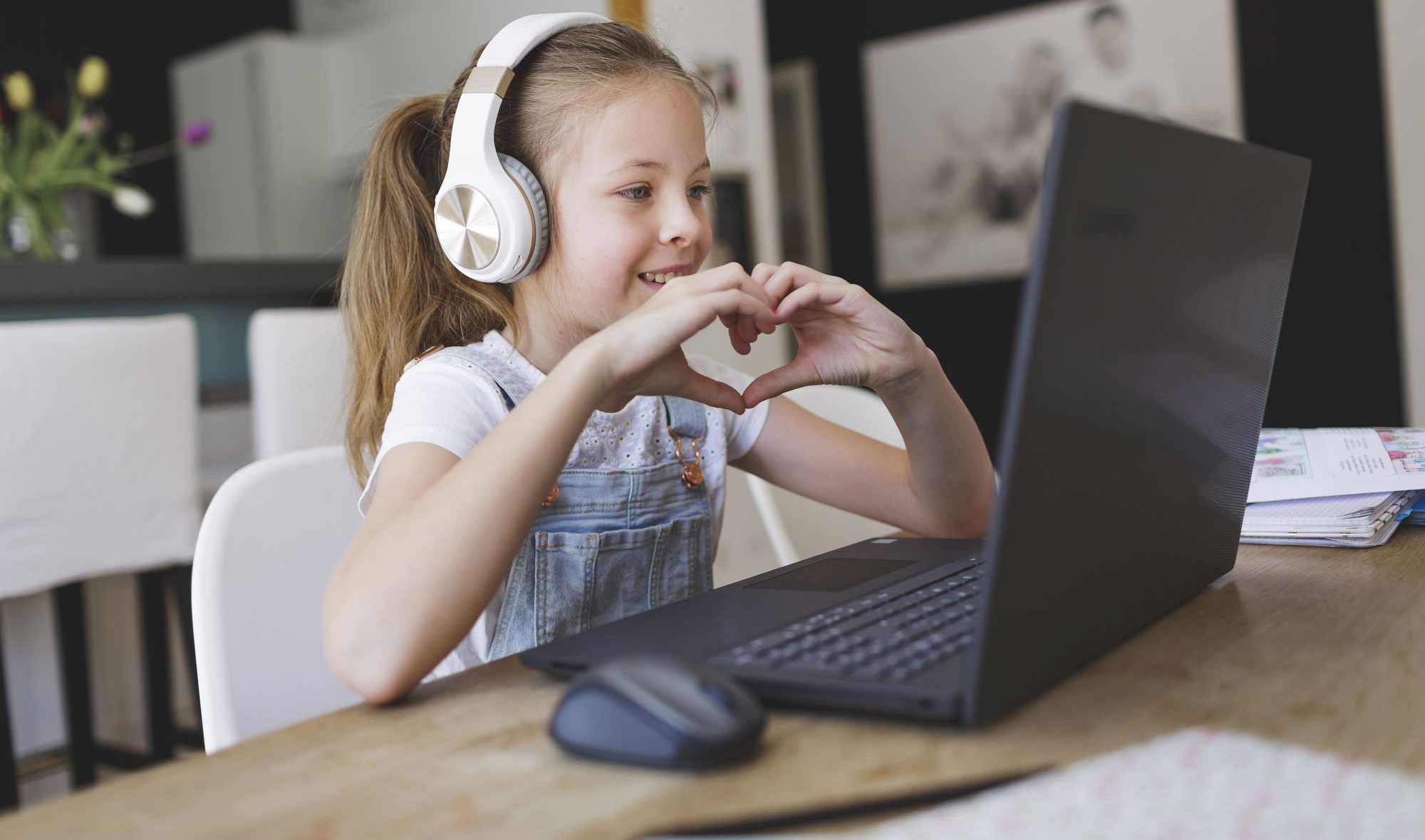 girl wearing headphones and attending online school via laptop